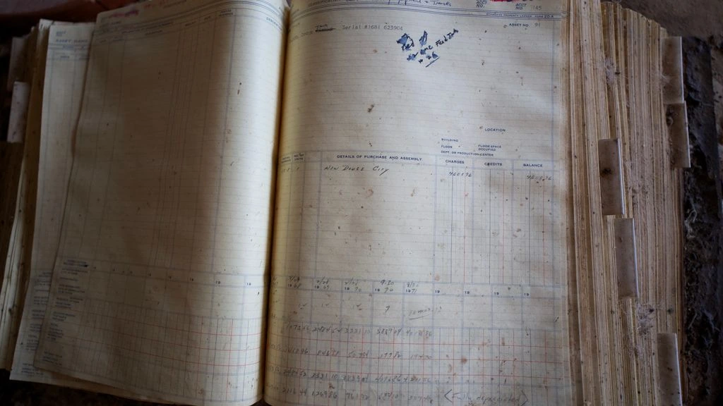 An archival ledger resting open on a desk, photographed in desaturated warm tones.